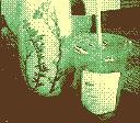 On the dining room table is an ice coffee cup, next to a vase with flower designs on it